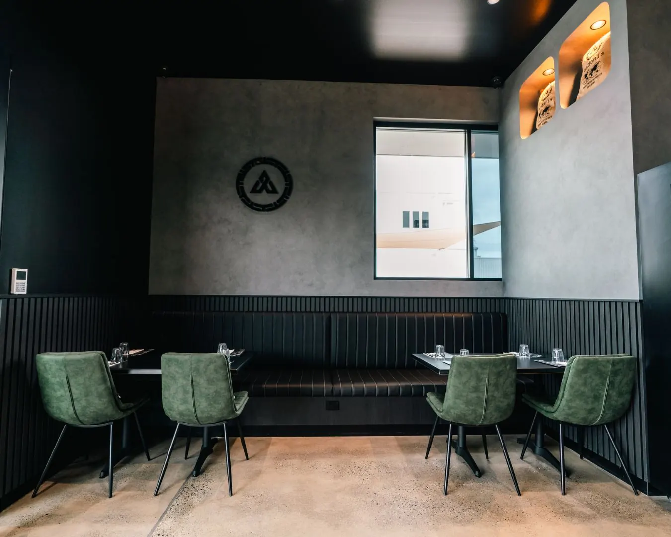 A dining room at an Andonis cafe, with green chairs and the Andonis emblem on the wall